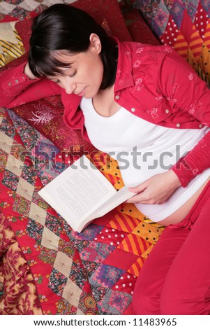 expectant mother smiles and reads book on the patchwork cover