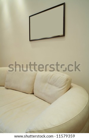 Fragment of the interior with soft beige sofa from leather and frame for picture