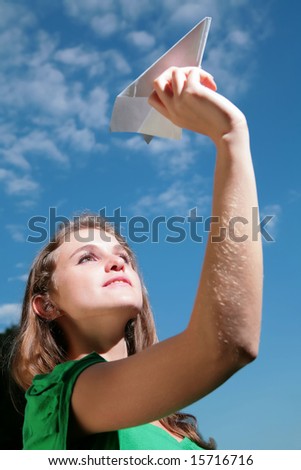 young girl starts paper plane in blue sky