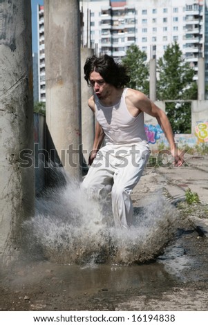 man in white cloth jumps in water, raising dripped