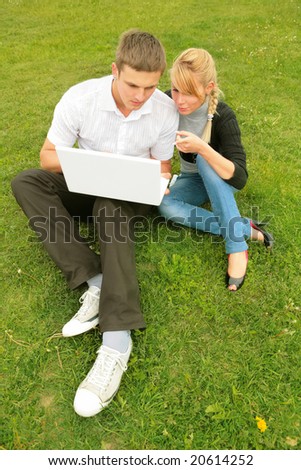 two young businessmen sit on herb with laptop and create prototype of the ecological production