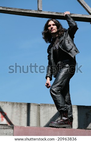young man with long hair in leather cloth gothic style