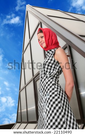 beautiful girl in red kerchief and plaid gown on background of the glass-metallic design
