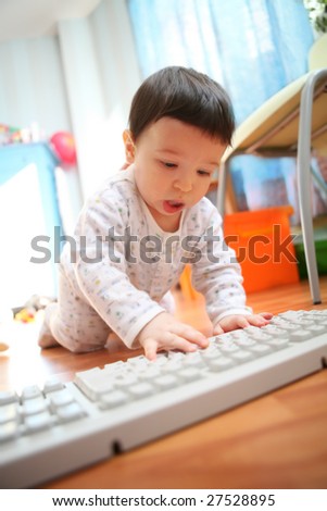 baby and computer keyboard in interior of the room, soft focus