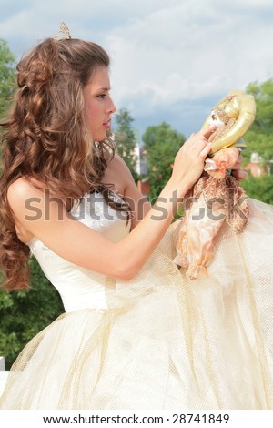 pretty princess in white-golden dress plays with loved doll