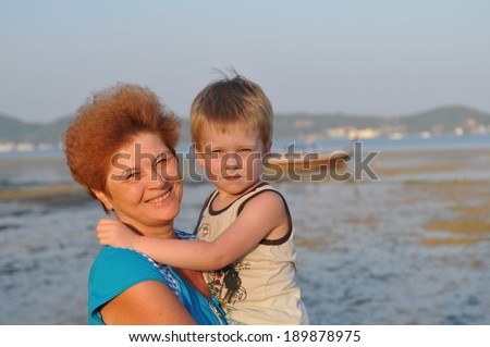 Grandmother and grandson portrait at the evening in front of sea portrait looking at camera