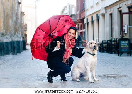 Pretty woman sits in old city with dog and looking at camera