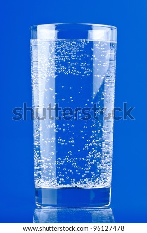 Glass of sparkling water on blue background