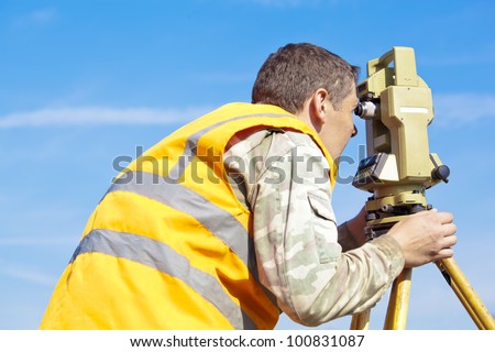 Surveyor engineer making measuring with optical equipment theodolite at blue sky background