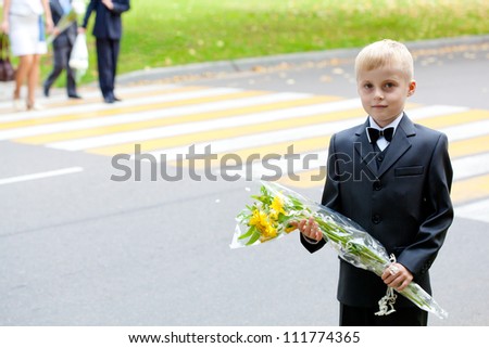 Drivers - please! September 1 children go to school. Schoolboy with flowers against the background of zebra crossing