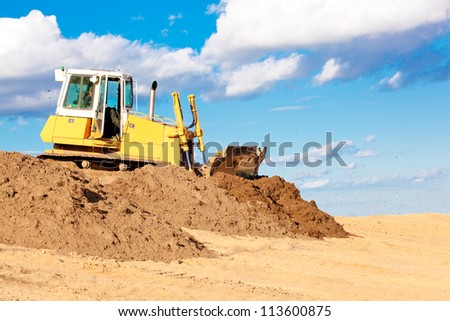 Bulldozer machine moving soil at construction site during earth moving works