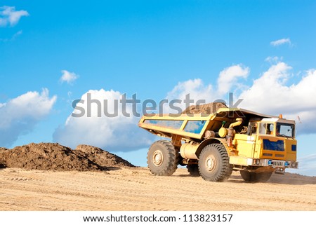 Heavy Dump Truck unloads soil on the sand at Construction Site
