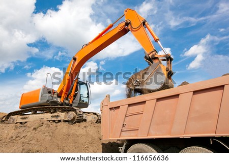 Excavator machine loading soil or sand into truck body