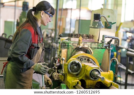 Metalwork industry. Factory woman turner working on workshop lathe machine