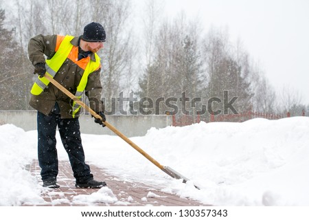 Man worker in uniform shoveling snow