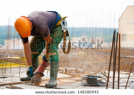 Industrial worker Cutting metal rebar at Construction site with an electric hand Grinder machine during tying steel bars for concrete reinforcement