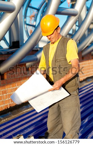 Builder worker with blue print at construction site