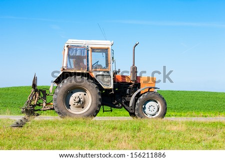 Tractor machine with grass cutter mowing lawn along road during machinery landscaping works