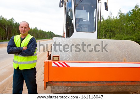 Heavy vibration roller and industrial worker during road construction