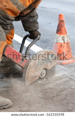 Cutting asphalt road for repair with angle grinder; road works; upgrading road surfaces; vertical orientation
