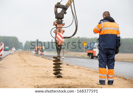 Builder Worker Monitoring Drilling Holes In Ground During Construction Road Works