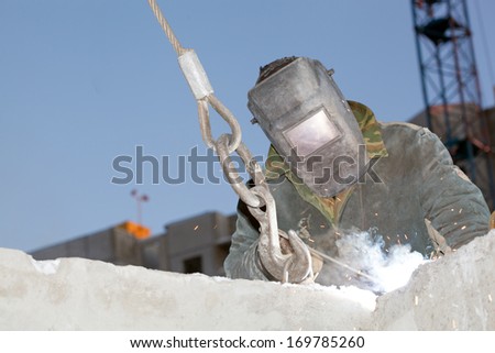 Industrial worker Welder welding metal rebar in reinforced concrete panels during hoisting construction works