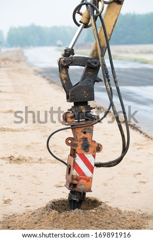 Drilling rig boring holes in soil during construction road works