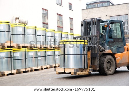 Forklift truck stacker transporting transformer steel roll cargo with pallet at factory warehouse
