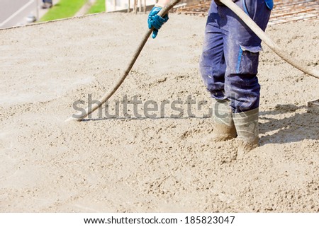 Concrete pouring works during commercial concreting floors; laborer compacting liquid cement into reinforcement form work