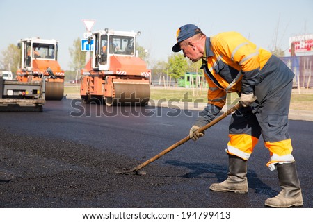 Construction Worker during Asphalting Road Works on Vibratory Rollers Machines background