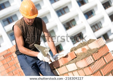 Bricklayer man worker installing brick with trowel during construction works