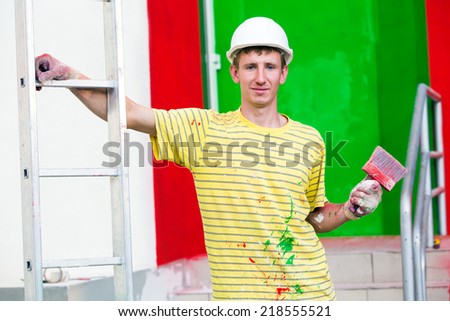 workman male painter with paintbrush and stepladder during decorating construction works  house facade