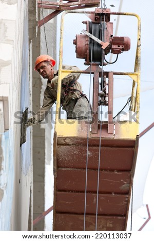 Plasterer builder man worker plastering house wall of bricks or concrete blocks during finishing construction works