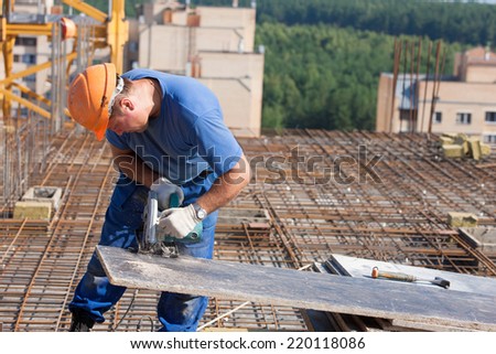 carpenter builder man worker cutting wood sheet with handheld circular saw machine during construction formwork works