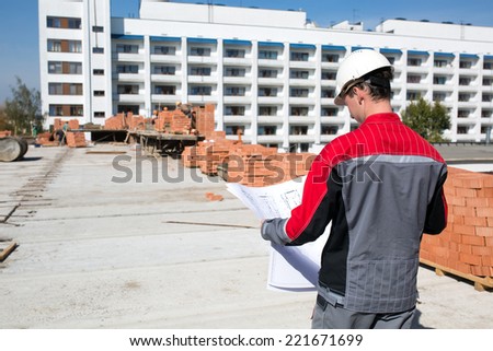 Builder worker with drawing at construction site