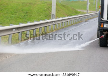 Road cleaning machine clearing roadside with water jet