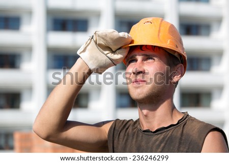 Builder man worker with hard hat looking into distance on construction site background
