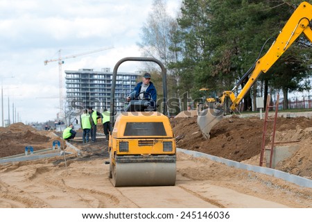 Man worker compacting soil with vibroroller machine during city road construction works crews