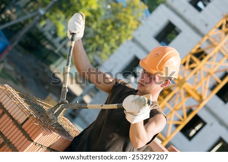 Construction manual bricklayer worker cutting armature grids with rebar cutters during masonry works