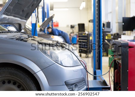 Servicing car air conditioner in auto repair shop