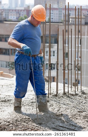 Construction worker compaction ready-mixed concrete with metal tool