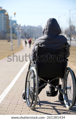 disabled handicapped person on wheeled chair during walk in city among people without disabilities