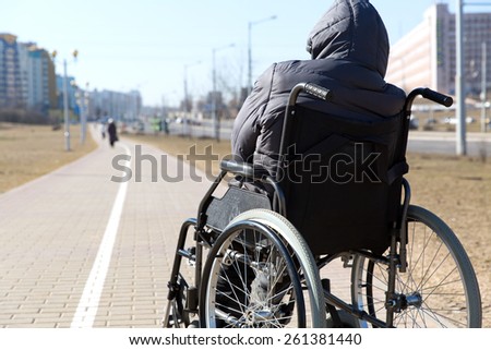 disabled handicapped person on wheeled chair among people without disabilities