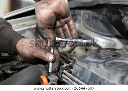 mechanic man worker with socket wrench during car repair works in auto service center