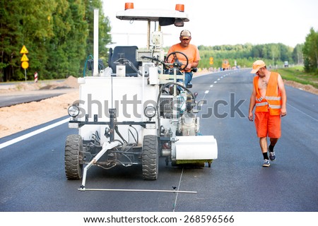 Teamwork: Pavement Asphalt Road Marking Paint and Striping with Thermoplastic Spray Applicator Machine during highway construction works