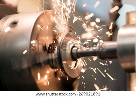 metalworking industry: finishing metal working on lathe grinder machine with flying sparks