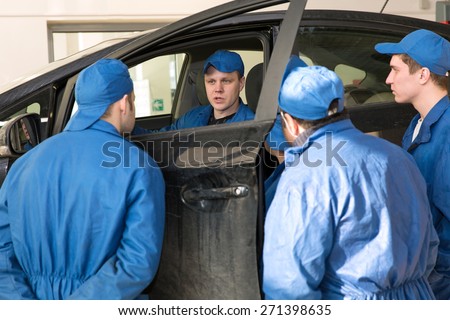 Teamwork: Group of Engineers and Mechanics People during Vehicle Repairing or Diagnostics Works in Car Service Garage