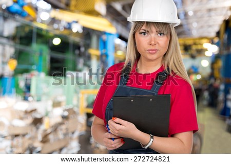 Industrial caucasian female inspector worker with clipboard at factory workshop background