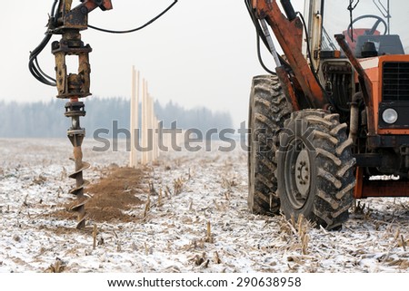 boring holes in ground with drilling rig during fence construction
