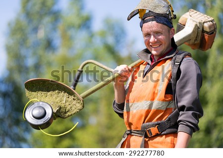 Portrait happy gardener or road landscaper man worker with gas grass trimmer equipment